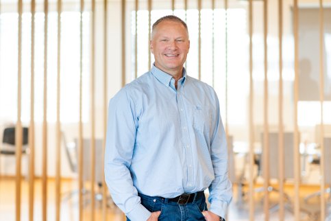 Portrettbilde av Ronny Lindås, konserndirektør IT og digitalisering i GK, tatt innendørs foran en spilevegg.
