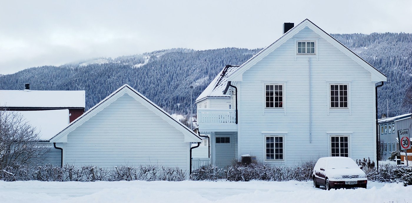 Hvit enebolig på vinteren med snø på taket