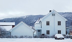 Hvit enebolig på vinteren med snø på taket