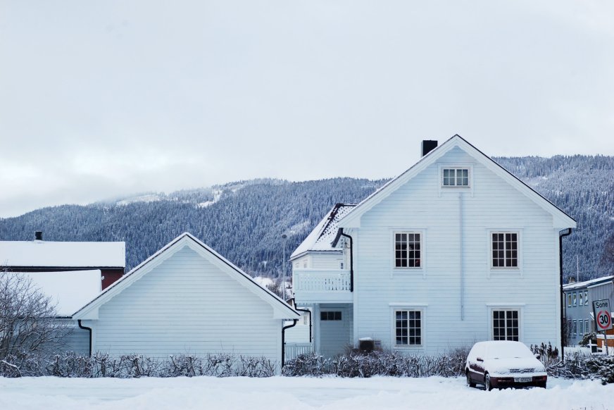 Hvit enebolig på vinteren med snø på taket