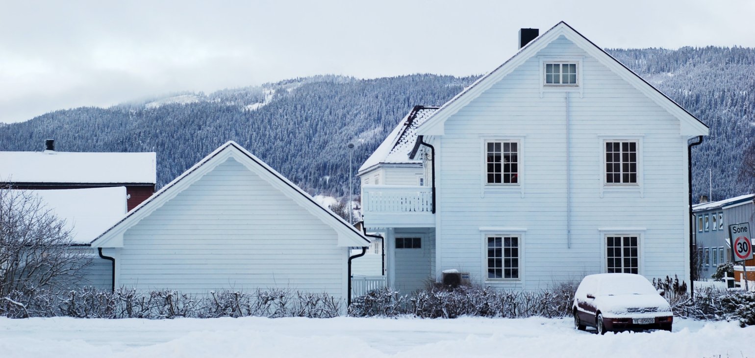 Hvit enebolig på vinteren med snø på taket