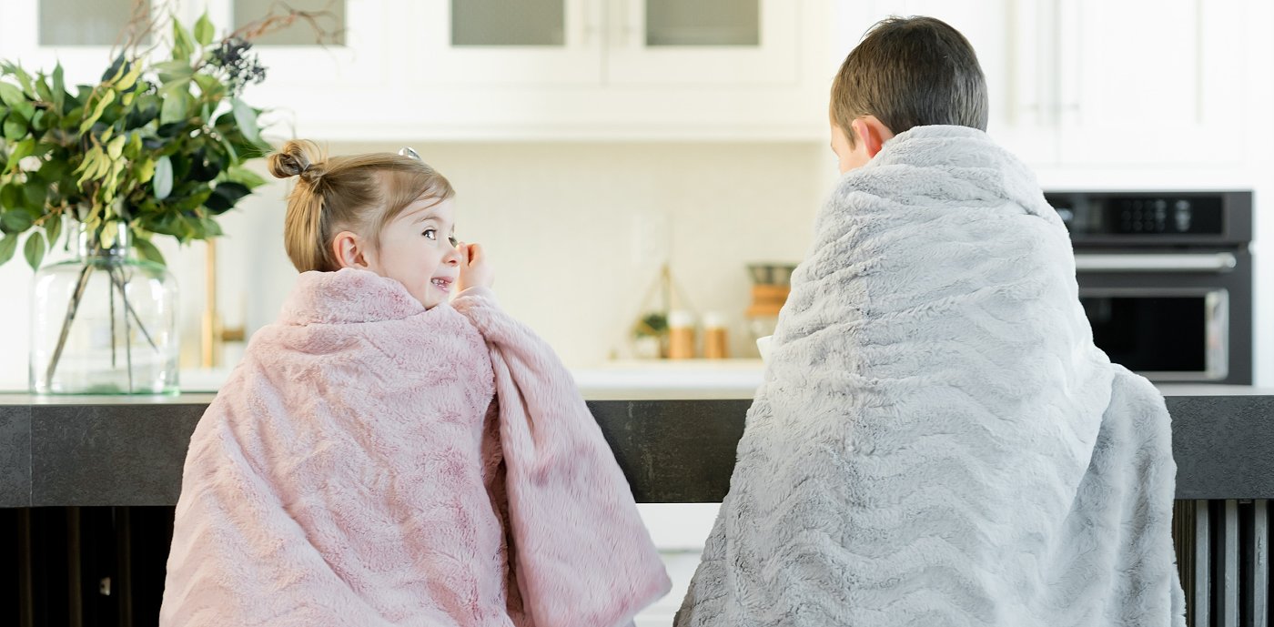 To barn under pledd på stoler ved kjøkkenbenken To barn under pledd på stoler ved kjøkkenbenken