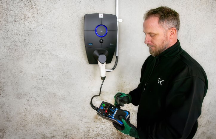 Elektriker i GK, Robin Markussen, sjekker at laderen fungerer som den skal. Foto: GK.
