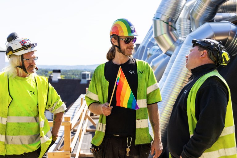 GK-ansatte med Pride-flagg og hjelm.